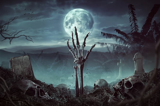 Рука скелета зомби поднимается в темную ночь Хэллоуина.