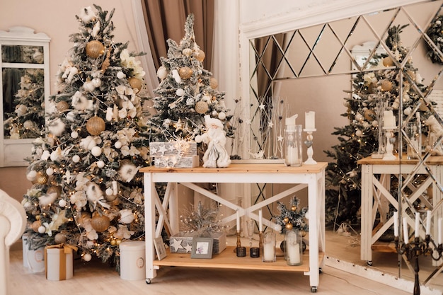 Фото Красивая новогодняя елка стоит в гостиной у стола с новогодним декором.