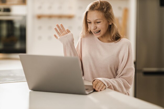 Фото Симпатичная девочка-подросток делает видеозвонок на ноутбуке у себя дома.