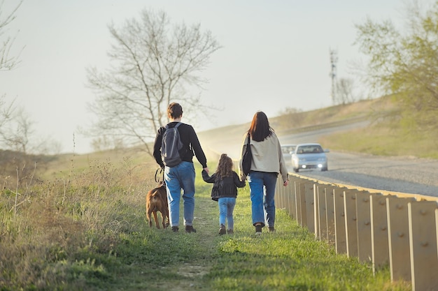 사진 강아지와 함께 여행하는 가족은 자동차와 함께 먼지가 많은 길을 따라 걷는다