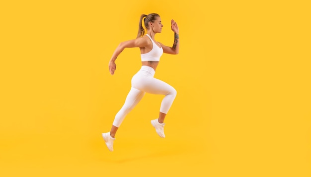 Активная фитнес-женщина бегает на желтом фоне