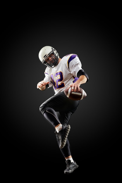 Photo american football player in a jump with a ball on a black