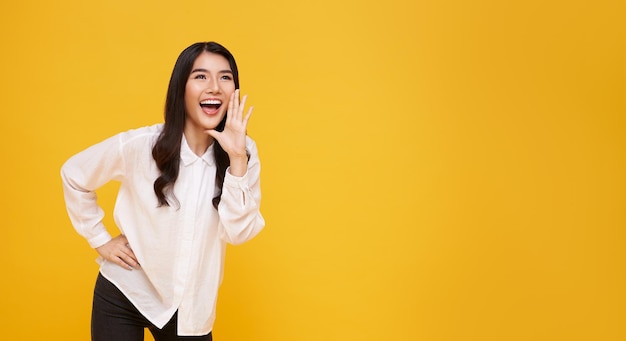 Photo asian woman with open mouths raising hands screaming announcement on yellow copy space background