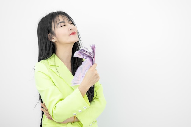 Photo asian woman smiling while holding thailand baht money in hands on white background asian woman celebrate happiness wealth happy money smiling face asian woman holding cash notes