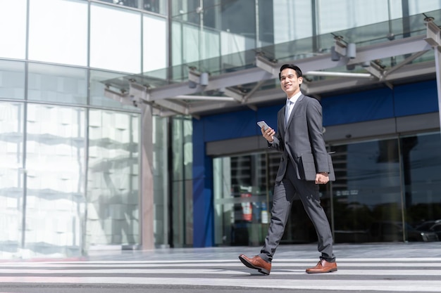 사진 스마트폰을 들고 흐릿한 건물 배경을 배경으로 걷는 아시아 남자 패션 비즈니스 사진