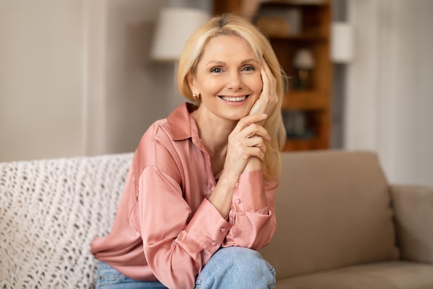 Photo attractive blonde senior lady posing touching face at home