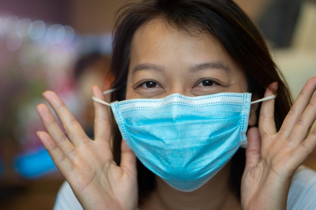 Aziatische vrouw die een beschermend masker op haar gezicht draagt om de pandemie van het COVID-19-virus te voorkomen.