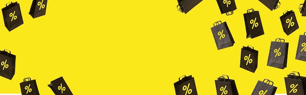 Фото Баннер с черными сумками продажи летают на желтом фоне. черная пятница творческая идея концепции