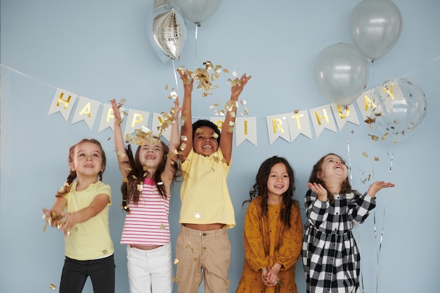 Воздушные шары и конфетти Дети на праздновании дня рождения в помещении веселятся вместе