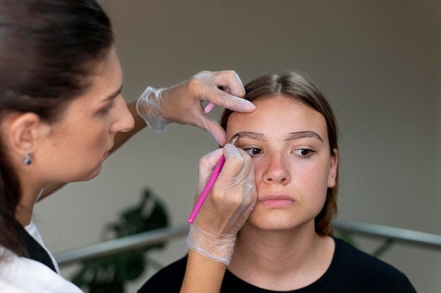 Photo beautician doing a microblading procedure on a young woman
