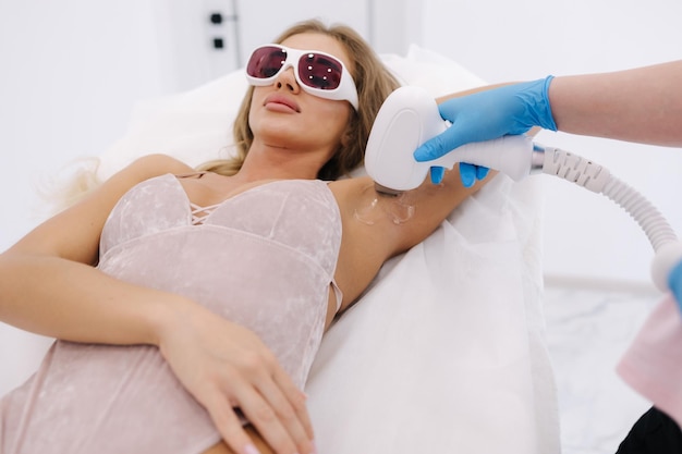 Photo beautician doing epilation on females armpit in beauty center woman receiving laser light hair