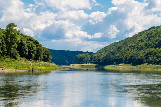 Фото Красивый пейзаж с голубой водой в реке и зелеными деревьями в лесу на горных холмах