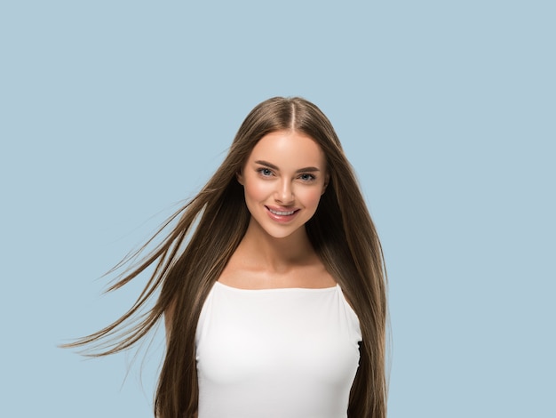 Photo beautiful woman with beautiful long smooth flying hair in white dress over color background