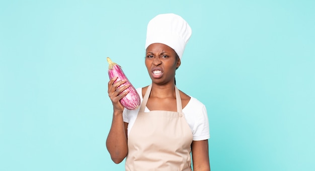 Black african american adult chef woman holding an eggplant