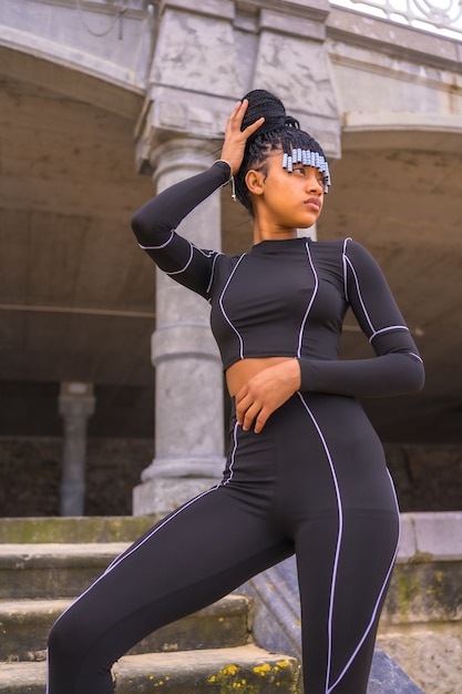 Фото Черная этническая девушка с косами с черным костюмом всего тела. pos © на лестнице рядом с пляжем