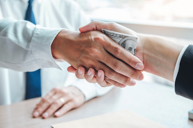 Businessman shaking hands giving dollar bills to business manager to deal contract
