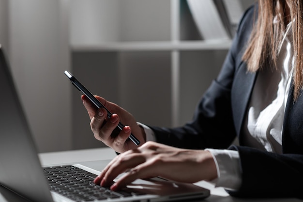 Фото Деловая женщина держит планшет в одной руке и печатает на ноутбуке с другой сидящей женщиной в офисе, представляя информацию на планшете и пишу на компьютере