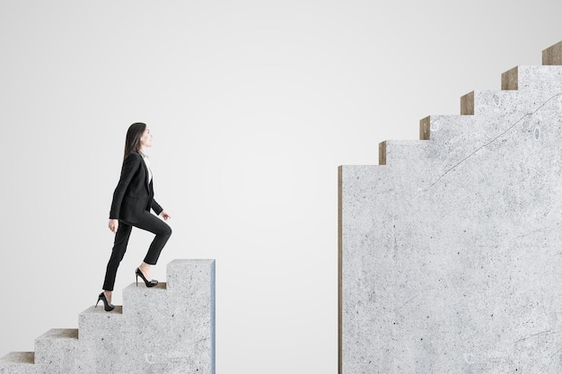 Фото Деловая женщина, идущая по бетонной лестнице на сером фоне концепция успеха и вызова
