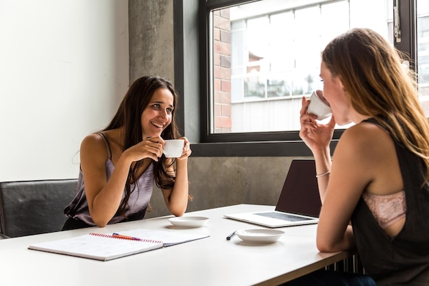 Фото Деловые женщины пьют кофе, разговаривая за столом в офисе.