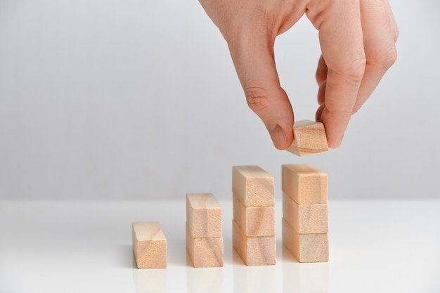 Фото Бизнес инвестиционная концепция. рука держит деревянные блоки на белом пространстве.