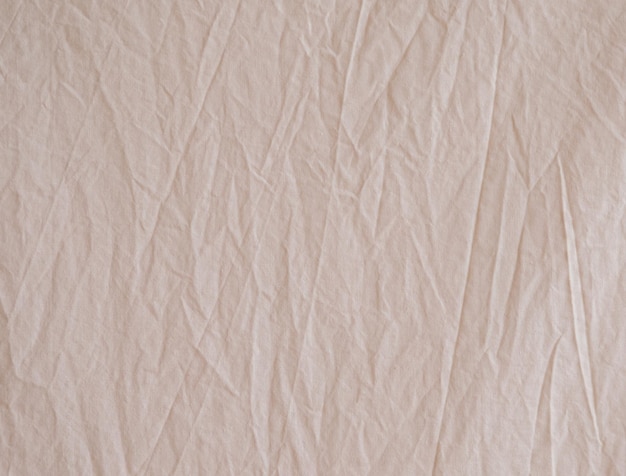 Фото Небрежно скомканная бежевая ткань как фоновое изображение неровная поверхность текстура хлопчатобумажной ткани
