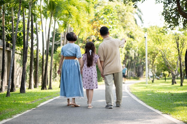 사진 관심 있는 할아버지 와 할머니 는 작은 손녀 의 손 을 잡고 공원 에서 함께  ⁇ 고 있다