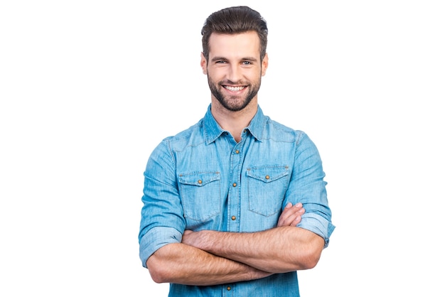 Photo casually handsome. confident young handsome man in jeans shirt keeping arms crossed and smiling while standing against white background