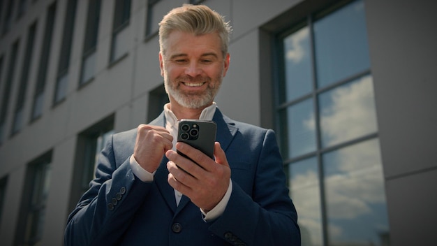 Photo caucasian happy old senior middle aged employer man mature businessman with phone achievement
