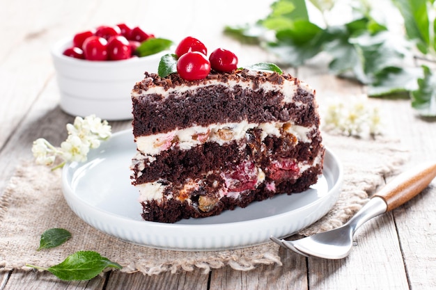 Chocolate sponge cake with cherries on a plate on a wooden table