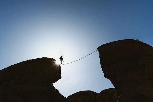사진 도전, 위험, 집중 및 용기 개념. 절벽 위에 밧줄에 걷는 남자 균형 실루엣