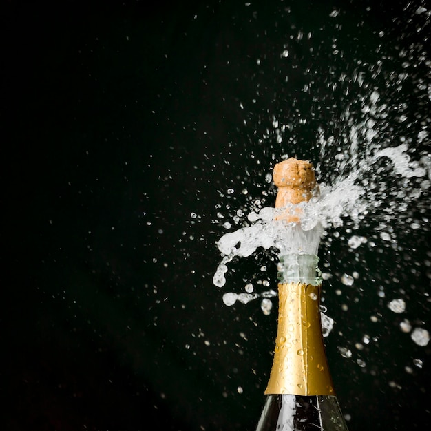 Фото Шампанское взрывается из бутылки на черном фоне