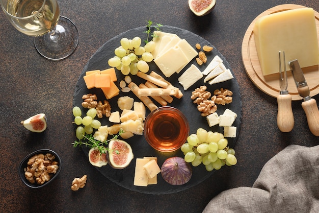 Сырное ассорти с виноградными орехами и инжиром на коричневом фоне, вид сверху
