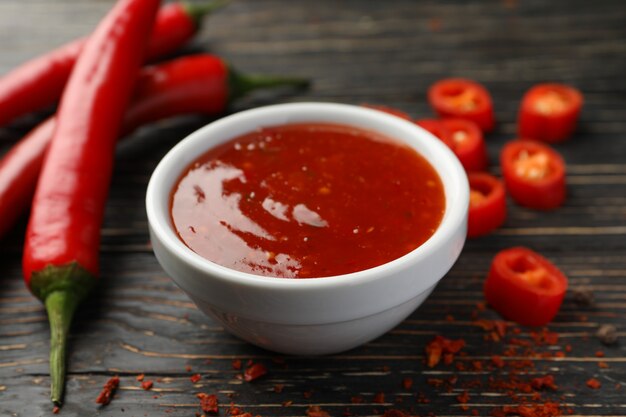 Photo chilli pepper and bowl of sauce on wooden  wall