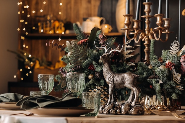 Рождественское украшение стола, Банкетный стол с бокалами перед подачей еды, Крупный план рождественского обеденного стола с сезонными украшениями, хрустальными бокалами и декоративным оленем