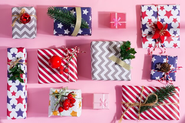 Photo colorful gift boxes with festive decoration on a pastel pink. flat lay.