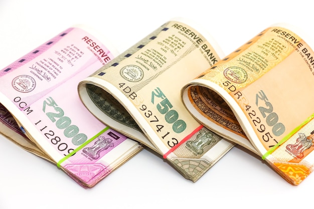 Крупным планом вид новых индийских банкнот номиналом 200, 500 и 2000 рупий на белом фоне.