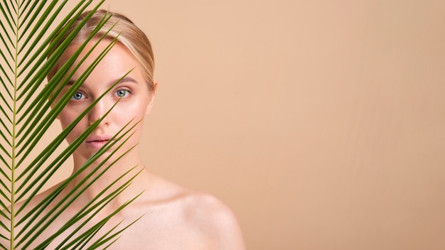 Close-up blonde model behind a plant with copy-space