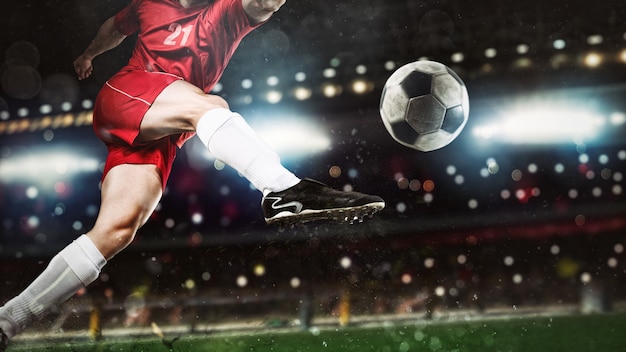 Фото Крупный план футбольной сцены в ночном матче с игроком в красной форме, бьющим по мячу с силой