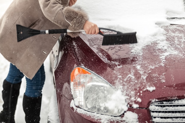 Крупным планом фото женщины, держащей кисть и уборки снега из автомобиля