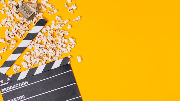 Фото clapperboard; попкорны и билеты в кино на желтом фоне