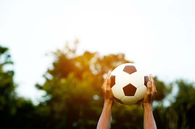 Фото Рука, держащая футбольный мяч против неба.