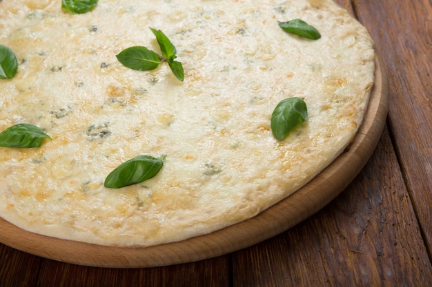 Delicious four cheese pizza with basil leaves
