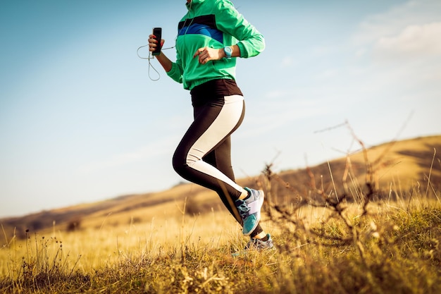 Foto dettaglio di una giovane donna urbana che fa jogging nella natura.