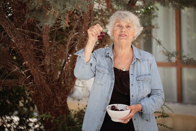 Photo elderly woman holding a bowl of ripe cherries