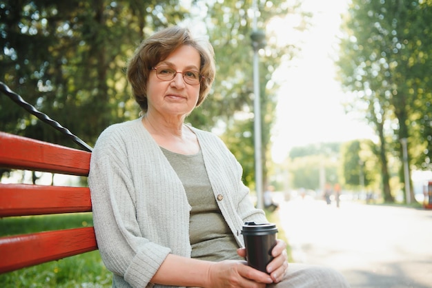 Photo an elderly woman sitting on bench in summer park