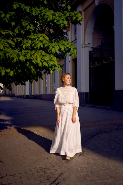 элегантная женщина среднего возраста в белом винтажном платье на фоне исторических зданий