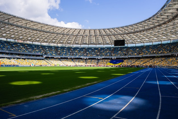 Фото Пустая синяя беговая дорожка на олимпийском стадионе на фоне пустых трибун