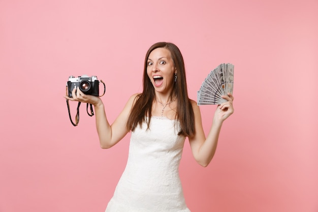 Фото Возбужденная счастливая женщина в белом платье держит пачку ретро старинных фотоаппаратов много долларов наличными деньгами, выбирая сотрудников, фотограф