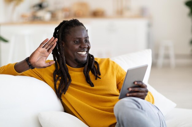 Externe communicatie zwarte man met behulp van digitale tablet voor video-oproep thuis