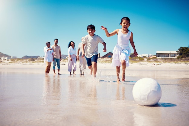 Familie voetbal strandvakantie en kinderen rennen langs de zee met geluk en vrijheid Voetbal jong meisje en ouders wandelen door de oceaan in de zomer op vakantie met kinderen op het zand met een glimlach